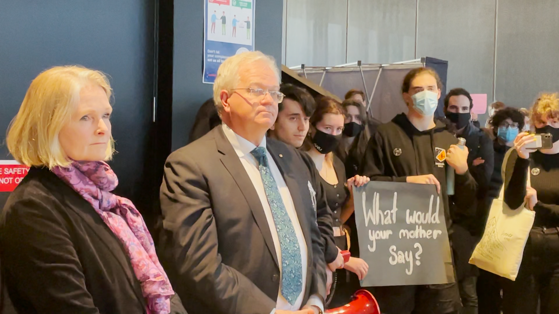 Brian Schmidt AC and Grady Venville, surrounded by student protestors who are expressing their discontent with the ANU's lack of action on a Human Rights Commission report into sexual harassment and assault on campus.